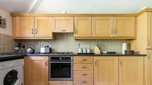 Een keuken met houten kastjes, een wasmachine, een oven en een betegelde spatwand.