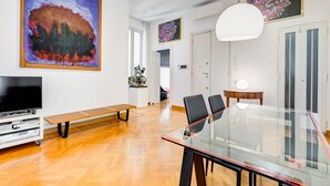 A modern dining area with a glass table, black chairs, and a bench. - Colosseum Terrace Apartment (Rome)