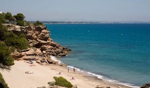A beach with rocky terrain and clear blue water.