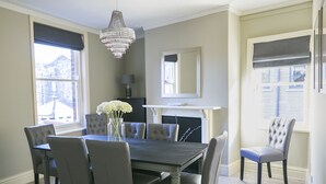 Una sala da pranzo con un tavolo rettangolare, sei sedie, un lampadario e un camino.