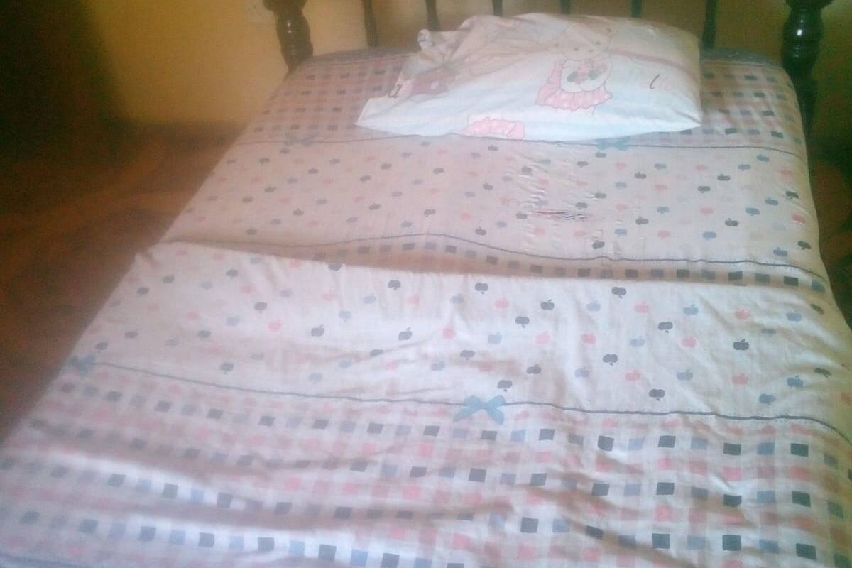 A bed with a checkered bedspread and a pillow with a cartoon character.