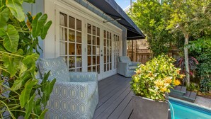 A covered deck with a pool, outdoor seating, and lush greenery. - QUEEN OF SOL ~ 3 Bed, 2 Bath in Peaceful Neighborhood with Dip Pool! (Key West)
