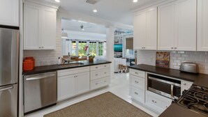 A modern kitchen with white cabinetry, stainless steel appliances, and a black countertop. - QUEEN OF SOL ~ 3 Bed, 2 Bath in Peaceful Neighborhood with Dip Pool! (Key West)