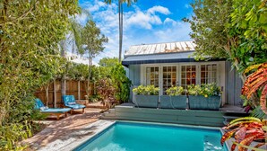 A backyard with a swimming pool, lounge chairs, and a wooden fence. - QUEEN OF SOL ~ 3 Bed, 2 Bath in Peaceful Neighborhood with Dip Pool! (Key West)