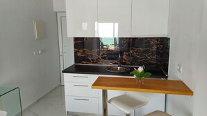 Una cocina compacta con protector contra salpicaduras de mármol negro, un lavamanos de acero inoxidable y una encimera de madera.