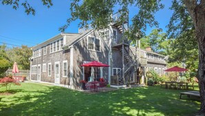 A two-story wooden house with a front porch, a staircase, and a red umbrella. - East End Condo w/ Beach Access! (Provincetown)