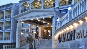 Exterior del Hotel & Spa Palamon Palace, con una entrada imponente, varios balcones y fachada bien iluminada.
