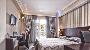 Habitación de hotel con cama, escritorio, silla y televisor.