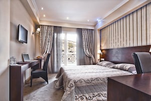 Habitación de hotel con cama, escritorio, silla y televisor.