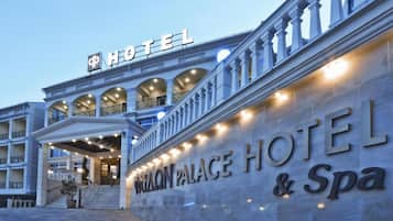 La entrada de un hotel con una fachada imponente, ventanas en arco y un letrero que dice 'Palace Hotel & Spa'.