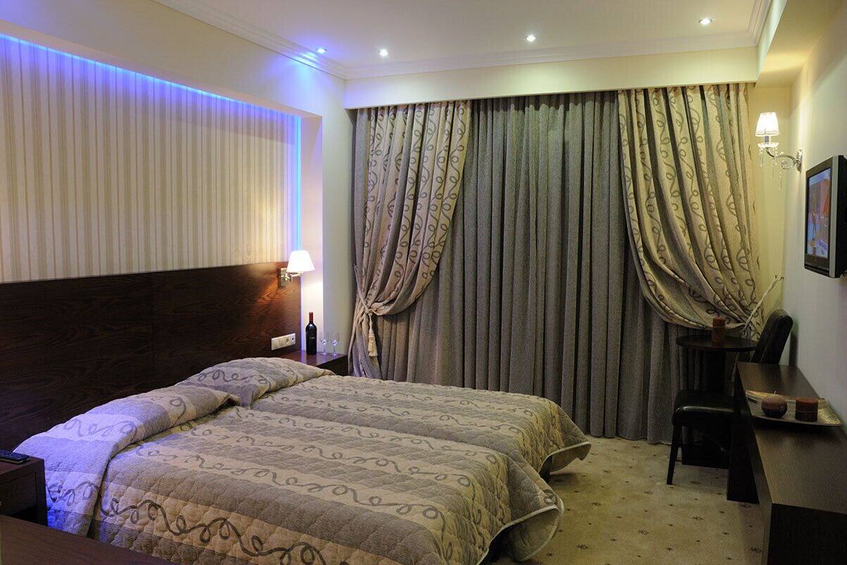 A hotel room with a large bed, a desk, a chair, and a TV.