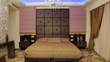 A bedroom with a large bed, a tufted headboard, a chandelier, and patterned floor tiles.
