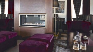 Una sala de estar moderna con chimenea, asientos cómodos y una zona de bar con vasos y botellas.