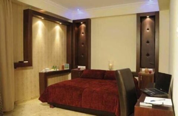 Une chambre d’hôtel avec un grand lit, un bureau avec un ordinateur portable et une table de chevet avec une lampe.