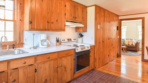 Una cocina con armarios de madera, una estufa y una cafetera.