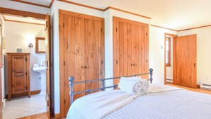 Un dormitorio con una cama grande, un armario de madera y un baño pequeño con lavamanos.