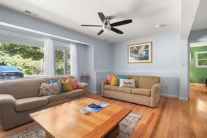 A living room with two sofas, a coffee table, and a ceiling fan. - Mins to Nauset Beach & Walkable to Town! (Orleans)
