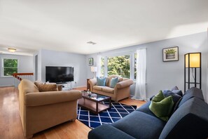 A modern living room with a large TV, two sofas, a coffee table, and a floor lamp.