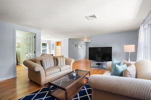 A living room with a sofa, a coffee table, a TV, and a lamp.