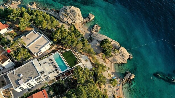 An aerial view of a coastal property with a swimming pool, beach access, and rocky terrain. - Luxury villa Colomba in Brela, seafront (Brela)