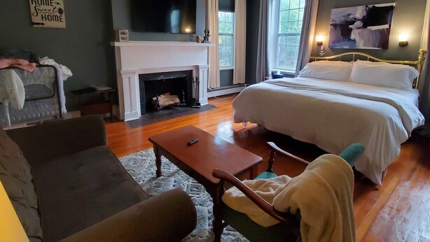 A bedroom with a large bed, a fireplace, a TV, and a sofa. - Located in the Historic downtown district, cozy studio, wifi. (Auburn)