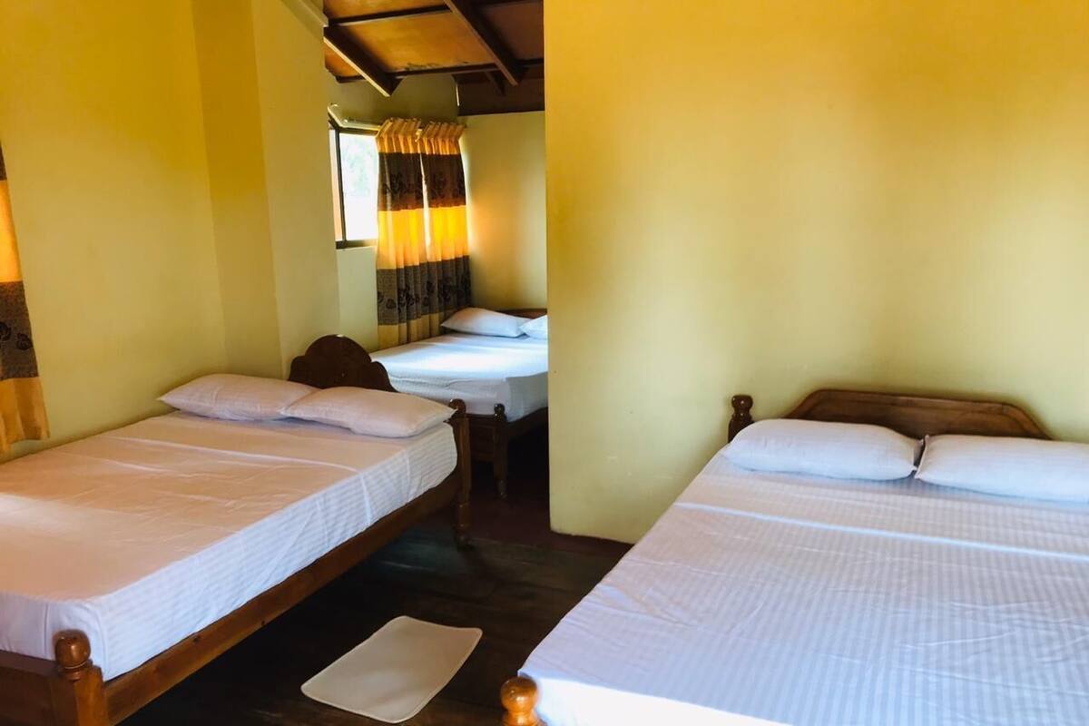 A room with two wooden beds, each with white bedding and a wooden headboard.