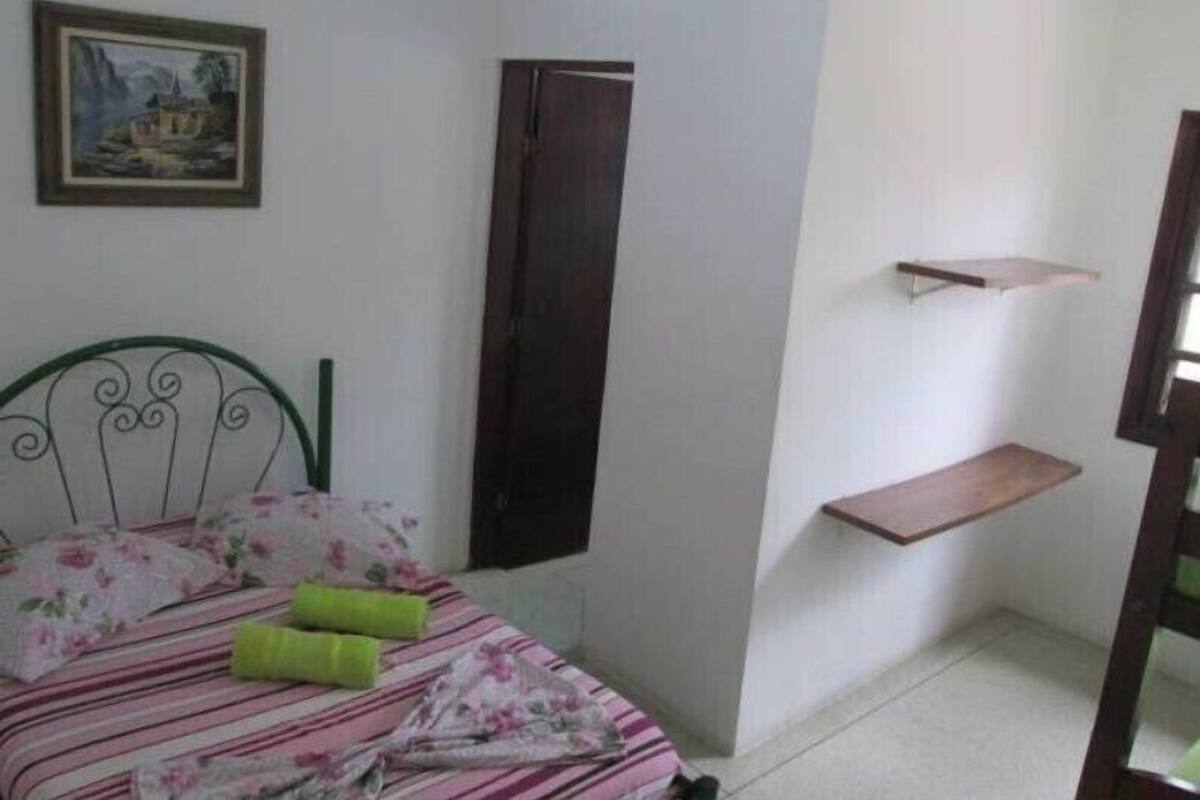Un dormitorio con una cama, un cuadro, un armario y una estantería.