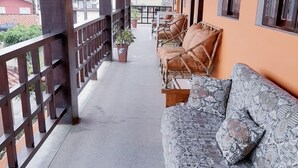 A covered outdoor seating area with wooden benches and a patterned sofa. - Pousada Nova Opção (Bertioga)
