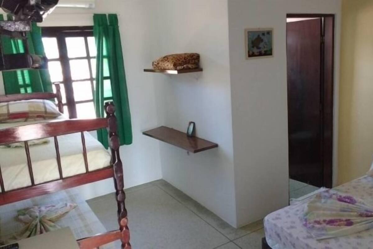 Un dormitorio con cama, una silla de madera, un estante pequeño y una puerta.