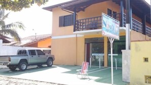 Un edificio de dos pisos con un balcón, una camioneta estacionada y un letrero.