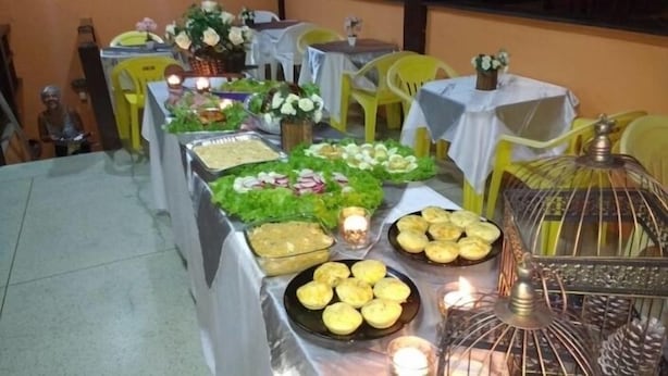 A buffet table with various food items and a decorative birdcage. - Pousada Nova Opção (Bertioga)