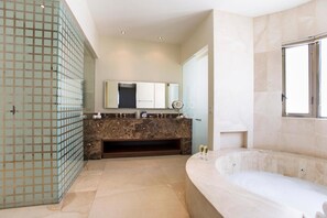 A modern bathroom with a marble vanity, a large bathtub, and a glass shower enclosure.