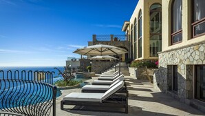 A poolside area with lounge chairs, a pergola, and a view of the ocean. - Villa in San Jose del Cabo 1023 (San José del Cabo)