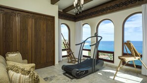 A spacious room with a treadmill, a wooden wardrobe, and a view of the ocean through large windows. - Villa in San Jose del Cabo 1023 (San José del Cabo)