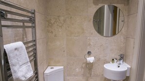 Et badeværelse med toilet, vask, håndklædetørrestativ og spejl.