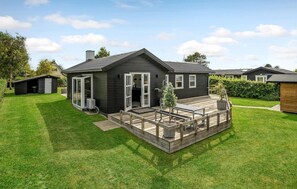 Ett modernt hus med en veranda, ett garage och en välskött gräsmatta.