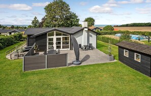 Ett modernt hus med en stor glasdörr, en inglasad uteplats och utsikt över havet.