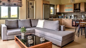 A modern living room with a grey sectional sofa, a wooden coffee table, and decorative items. - Modern Villa with Panoramic Sea Views (8JQW+PXC Arkadi, Greece)