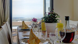 A dining table set with plates, glasses, a wine bottle, and a potted plant. - Modern Villa with Panoramic Sea Views (8JQW+PXC Arkadi, Greece)