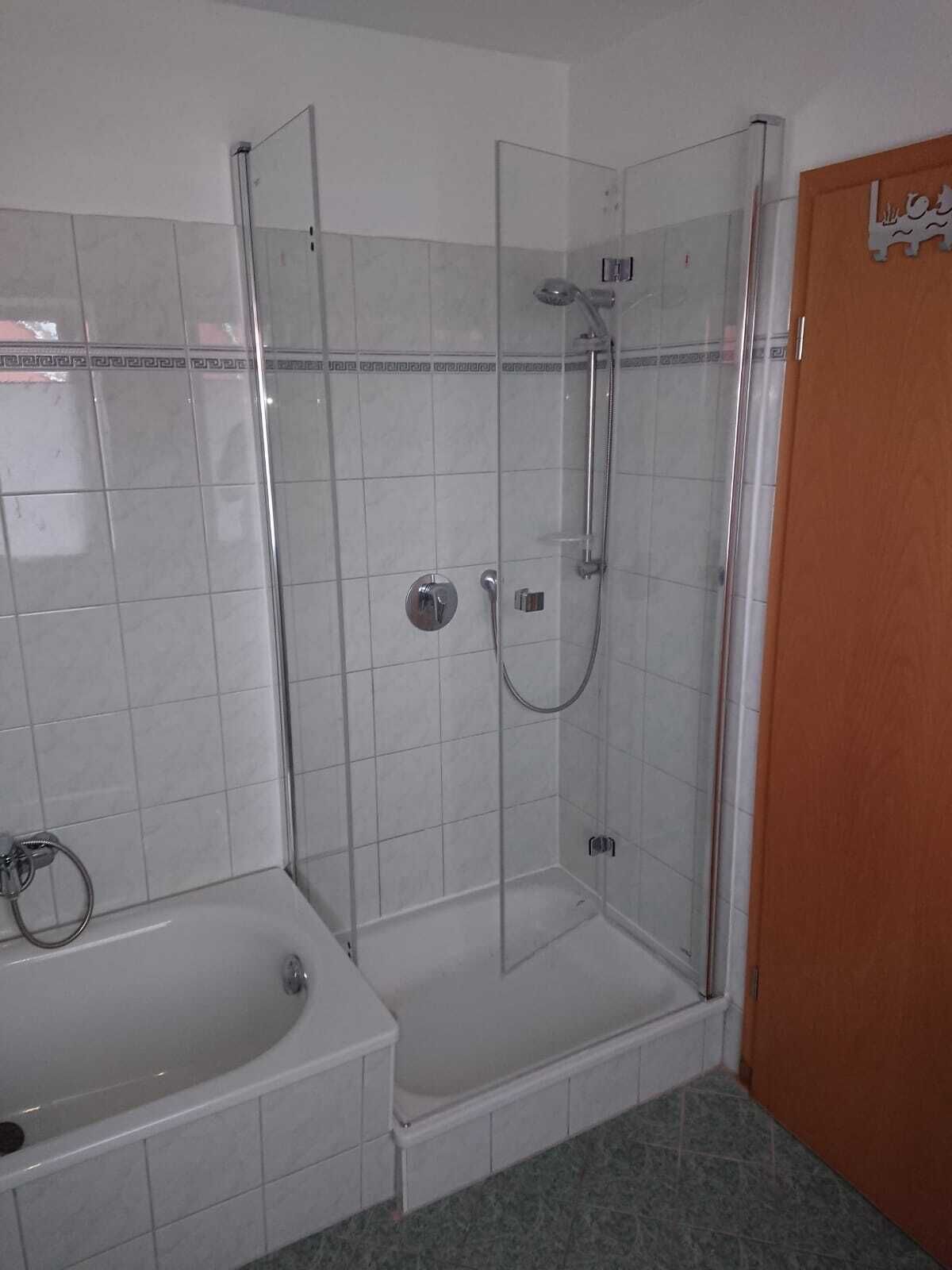 A bathroom with a glass-enclosed shower, a bathtub, and a toilet.