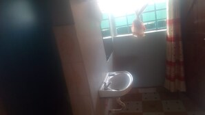A bathroom with a sink, a window with a view, and a tiled floor. - Kimbo Pefa Guest House (Ruiru)