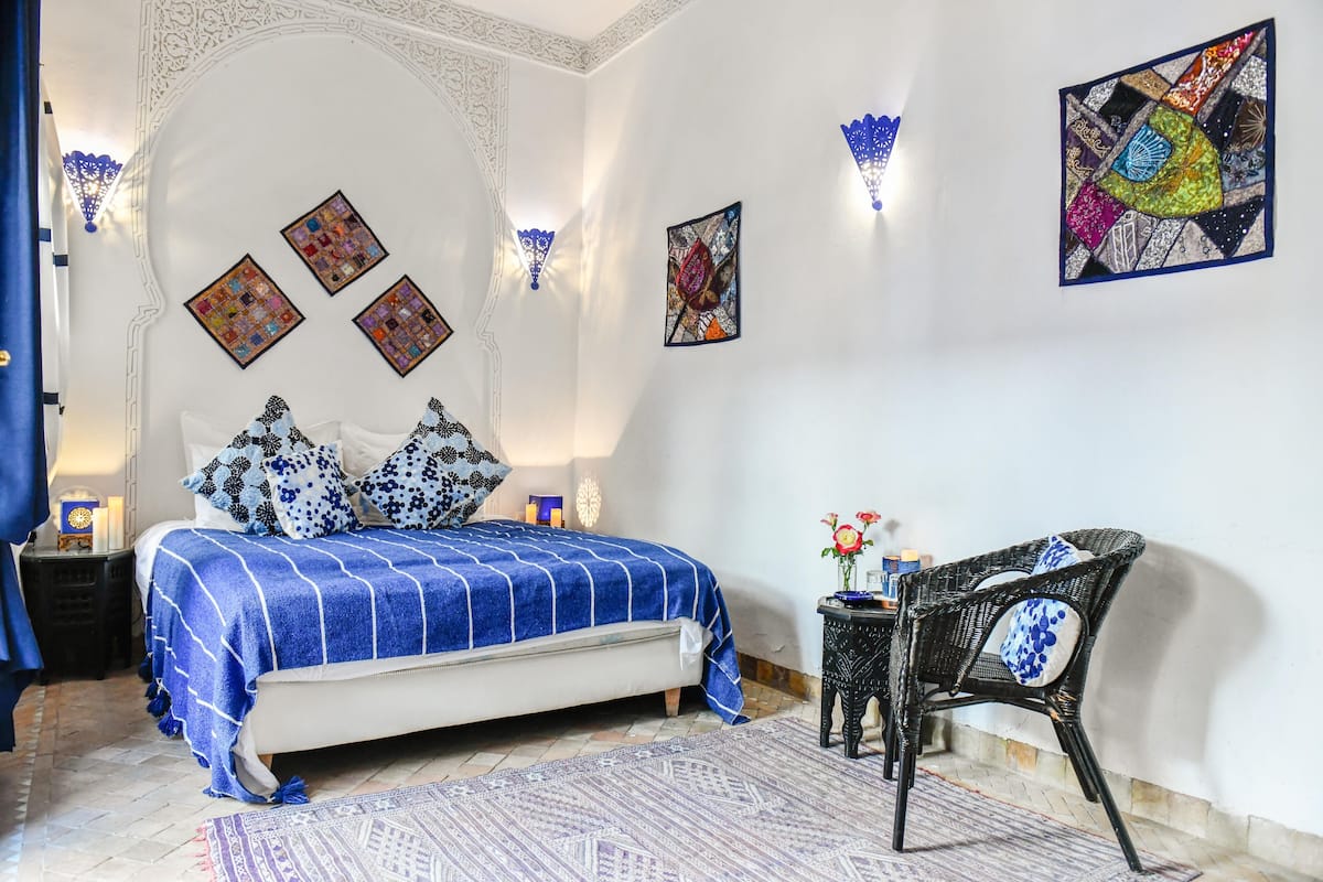 A bedroom with a bed, a chair, and decorative wall art.