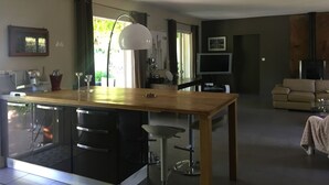Una cocina moderna con una isla de madera, armarios negros y un ventanal grande.
