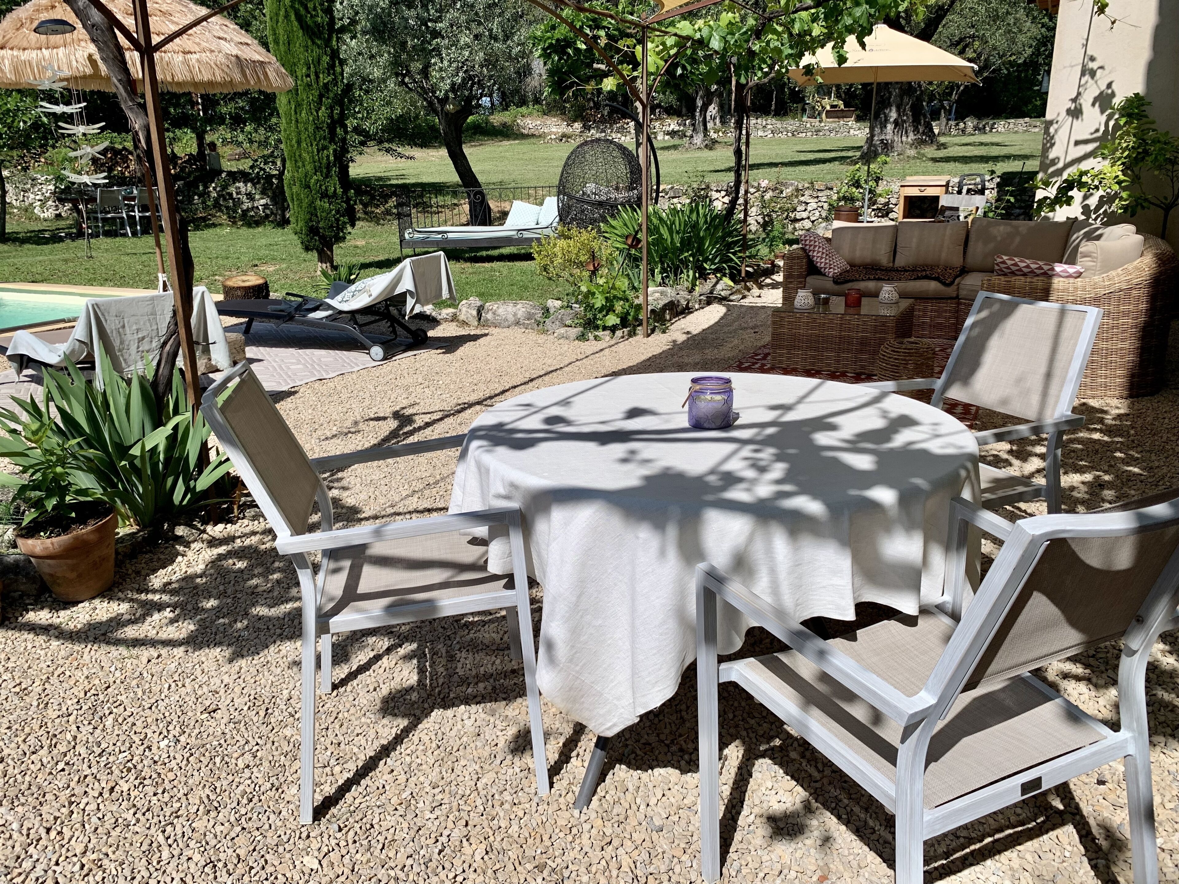 An outdoor patio area with a round table, white chairs, and a covered seating area.