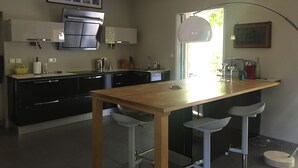 Una cocina moderna con una mesa de madera, taburetes de bar y un ventanal grande.