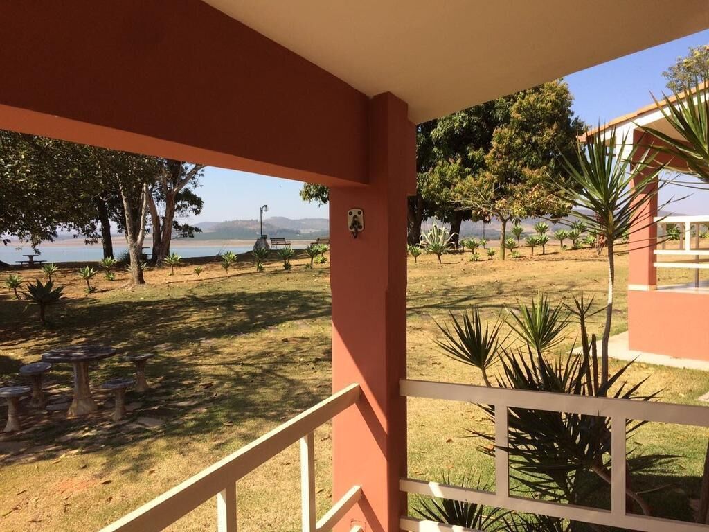 Área externa coberta com vista para um lago e árvores.