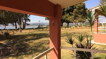 Área externa coberta com vista para um lago e árvores.