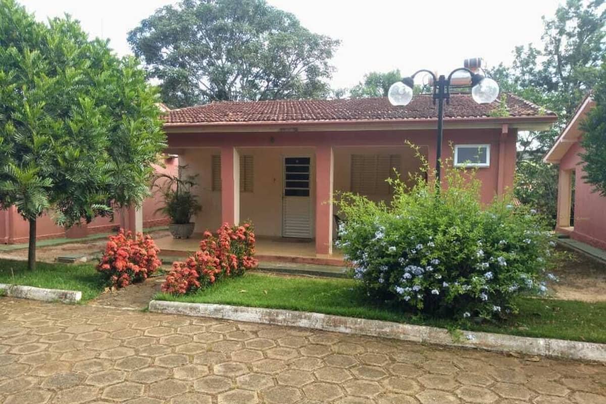 Une maison avec un toit en tuiles, un porche et un jardin agrémenté de fleurs et d’arbustes.