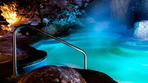 A hot spring with a metal ladder, surrounded by rocks and a snowy environment. - Bondurant by Tremblant Platinum (Mont-Tremblant)