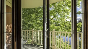 A balcony with a white railing, a metal bench, and a view of a lake surrounded by trees. - Bondurant by Tremblant Platinum (Mont-Tremblant)